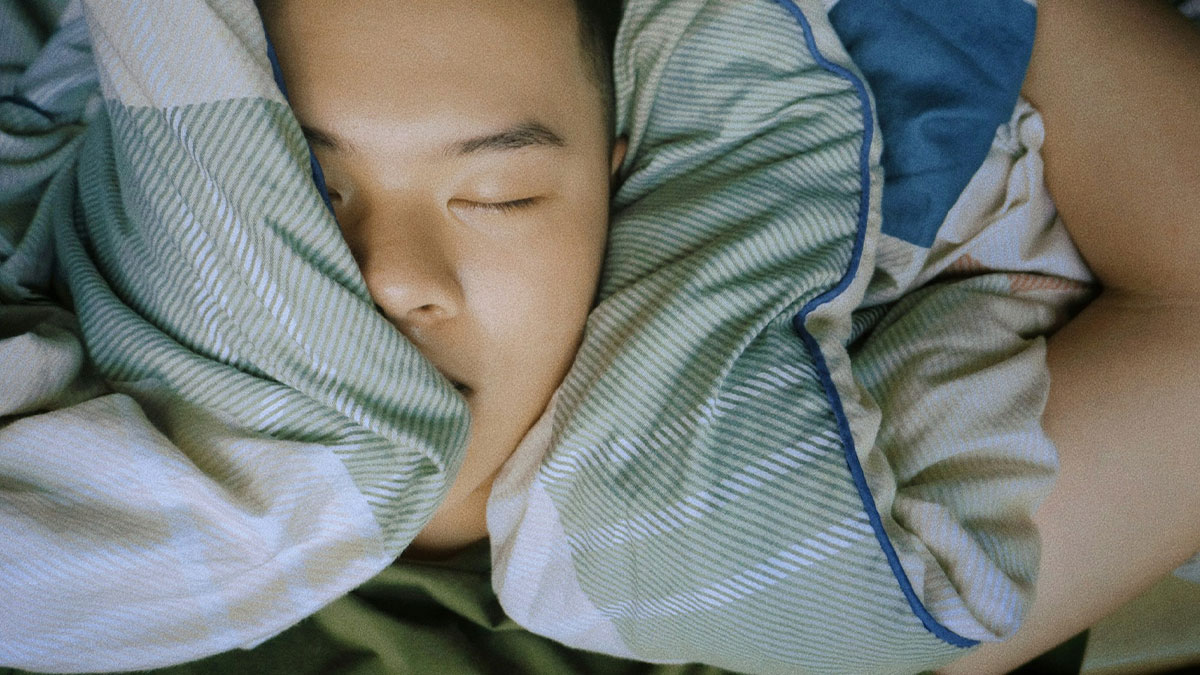 Person sleeping peacefully wrapped in a blanket, representing terrifying medical conditions without showing any symptoms.