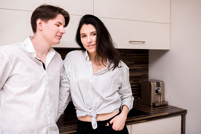 Young siblings in a kitchen with the golden child brother looking entitled while the scapegoat sister stays firm and calm. Young siblings in a kitchen with the golden child brother looking entitled while the scapegoat sister stays firm and calm.