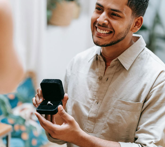 Man smiling and holding an open ring box proposing as a Christmas gift but facing a reality check. Man smiling and holding an open ring box proposing as a Christmas gift but facing a reality check.