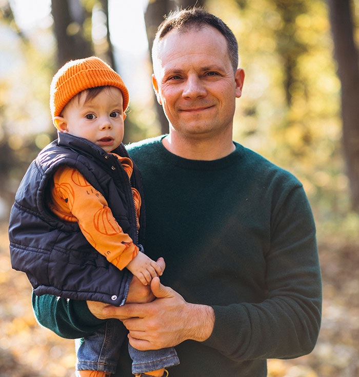 Man holding toddler outdoors in autumn, representing 91 men anonymously revealing thoughts without judgment.