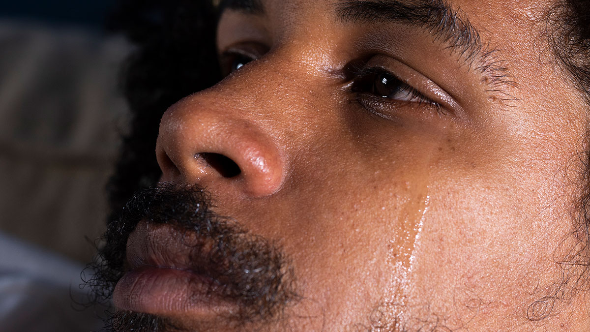 Close-up of a man with a tear on his cheek, reflecting emotions men anonymously reveal without being judged.