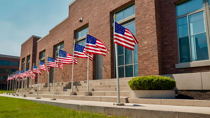 Row of American flags outside a school building, illustrating security concerns like metal detectors at school.