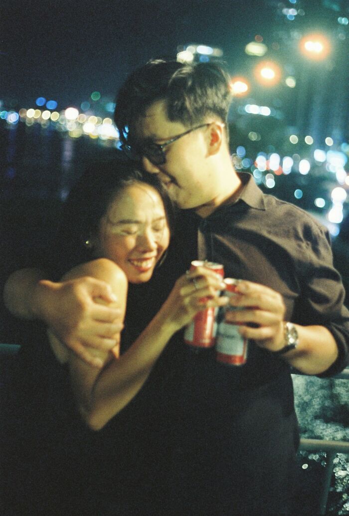 Young couple embraces happily at night holding drinks, illustrating love and friendship moments before broken trust occurs.