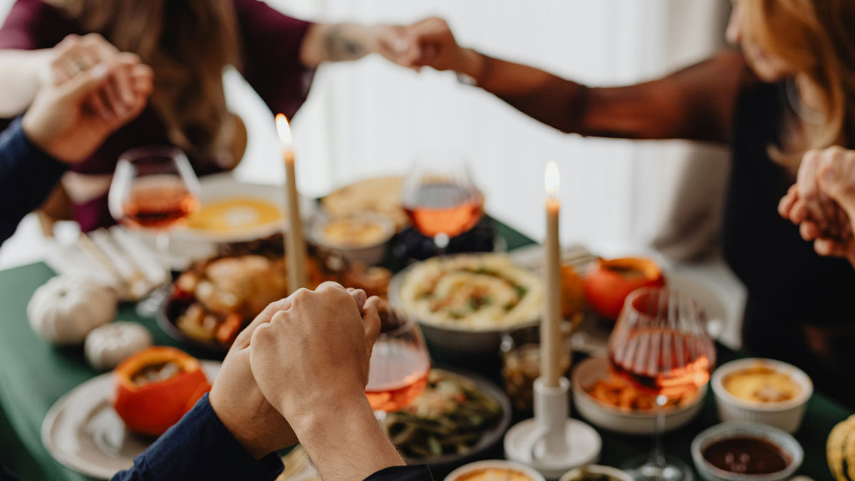 People holding hands around a dining table with candles and wine, reflecting tense MIL text message situations.