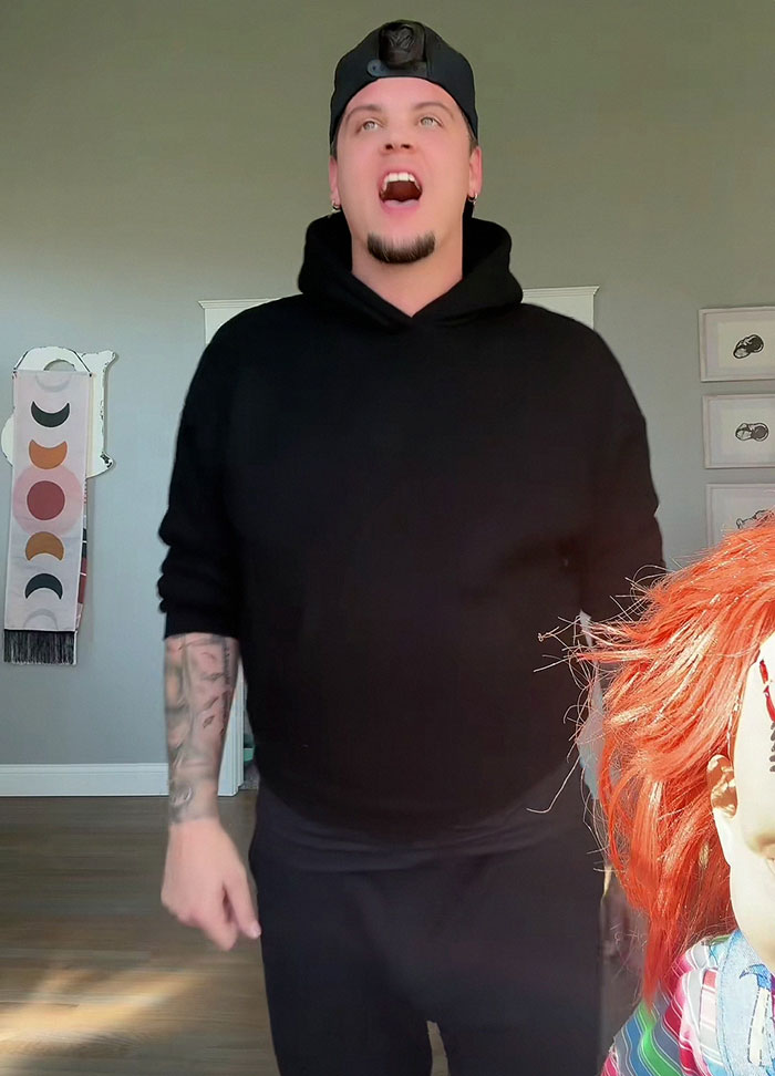 Man in black hoodie and cap standing indoors next to a doll with red hair, celebrity revealed more than they should 2025 frenzy. Man in black hoodie and cap standing indoors next to a doll with red hair, celebrity revealed more than they should 2025 frenzy.