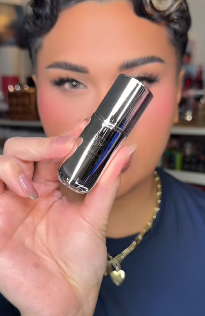 Person holding a shiny silver Dior product, highlighting luxury beauty item linked to Dior advent calendar controversy. Person holding a shiny silver Dior product, highlighting luxury beauty item linked to Dior advent calendar controversy.