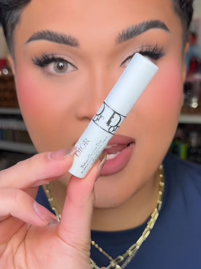 Person holding a Dior beauty product close to face, highlighting luxury brand associated with a $1,000 advent calendar controversy. Person holding a Dior beauty product close to face, highlighting luxury brand associated with a $1,000 advent calendar controversy.