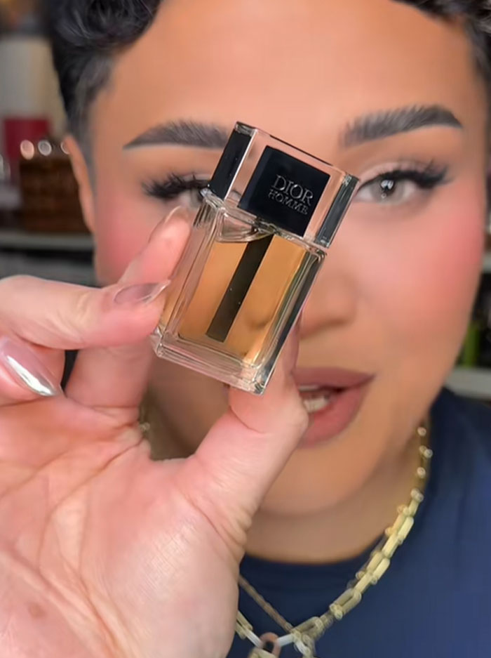 Person holding a small Dior Homme perfume bottle, highlighting luxury brand in a close-up beauty video. Person holding a small Dior Homme perfume bottle, highlighting luxury brand in a close-up beauty video.