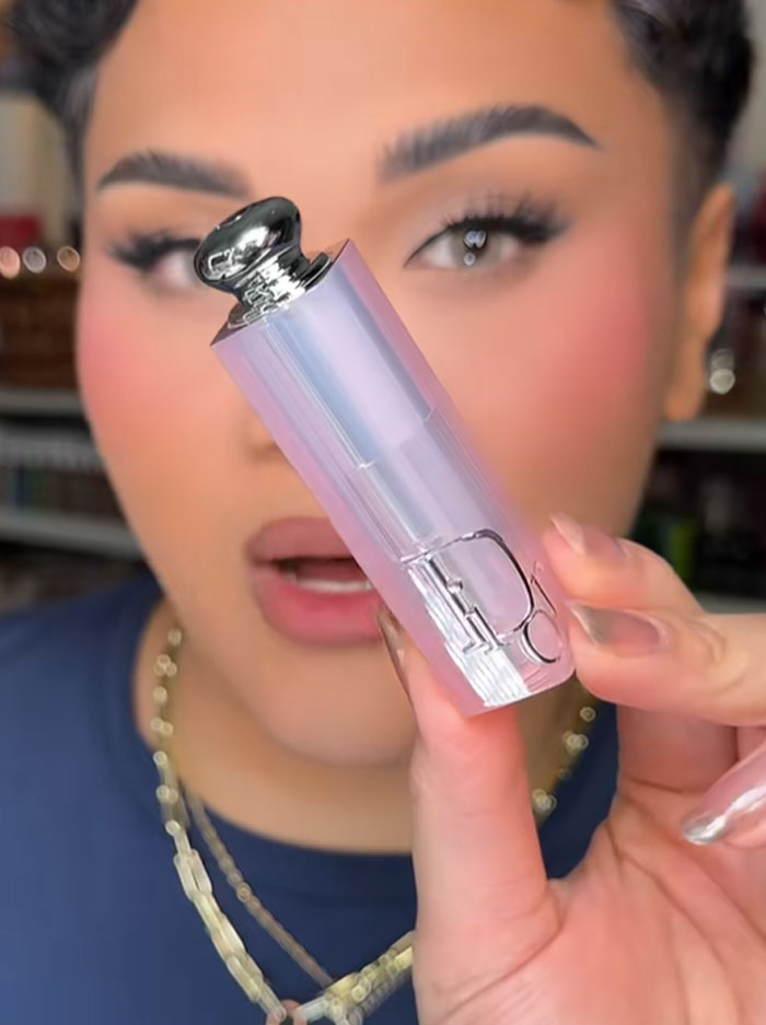 Person holding a Dior lipstick from the $1,000 advent calendar with a blurred background and focused facial makeup. Person holding a Dior lipstick from the $1,000 advent calendar with a blurred background and focused facial makeup.