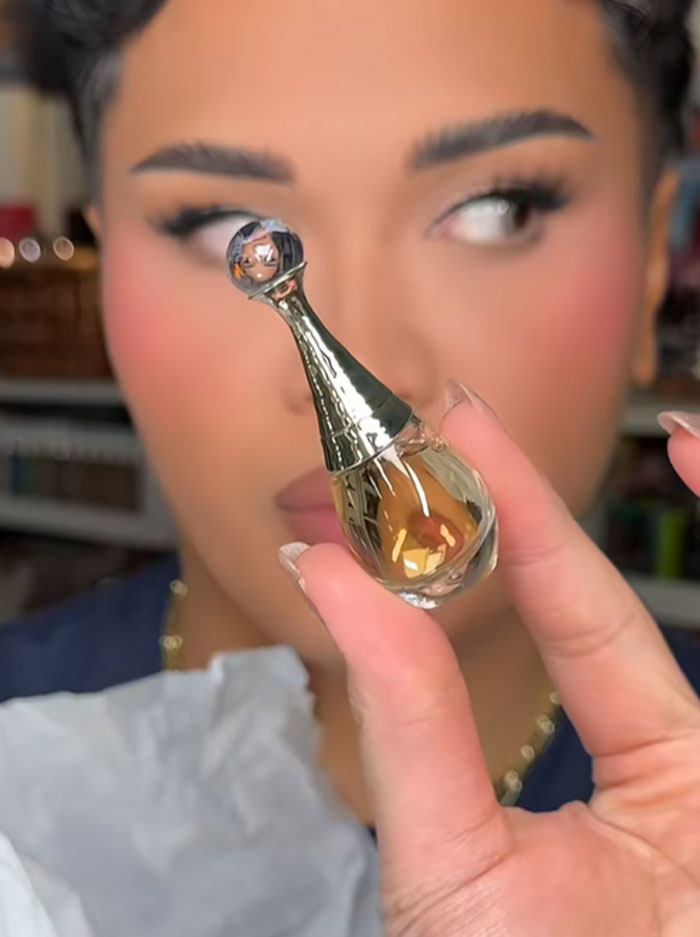 Person holding a small Dior perfume bottle, highlighting luxury beauty item from Dior advent calendar. Person holding a small Dior perfume bottle, highlighting luxury beauty item from Dior advent calendar.
