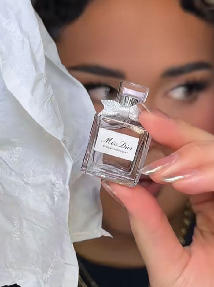 Close-up of a hand holding a mini Miss Dior perfume bottle from a luxury advent calendar by Dior. Close-up of a hand holding a mini Miss Dior perfume bottle from a luxury advent calendar by Dior.