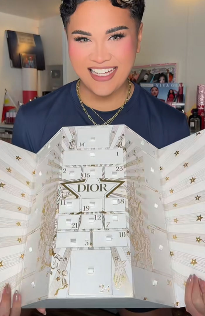 Person holding and displaying a Dior advent calendar with numbered compartments and decorative star patterns. Person holding and displaying a Dior advent calendar with numbered compartments and decorative star patterns.