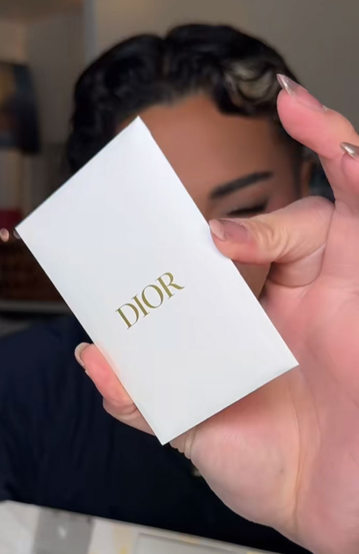 Person holding a white Dior advent calendar box with gold lettering, highlighting the luxury holiday product. Person holding a white Dior advent calendar box with gold lettering, highlighting the luxury holiday product.