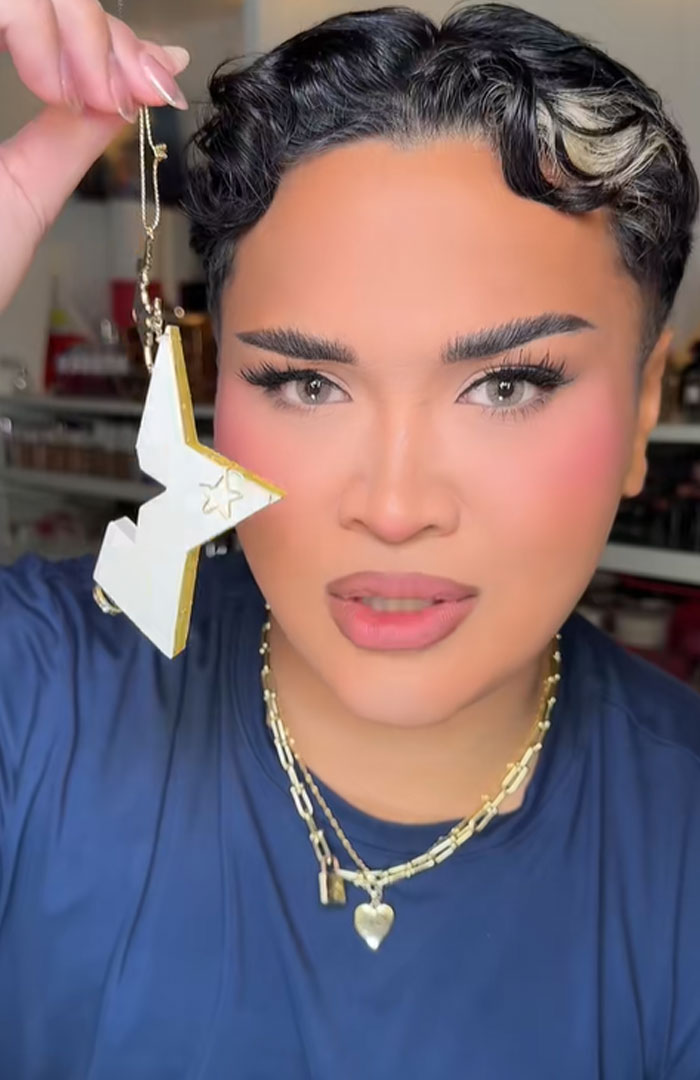 Person holding a star-shaped ornament from Dior advent calendar, showcasing luxury holiday item with neutral makeup and gold necklaces. Person holding a star-shaped ornament from Dior advent calendar, showcasing luxury holiday item with neutral makeup and gold necklaces.