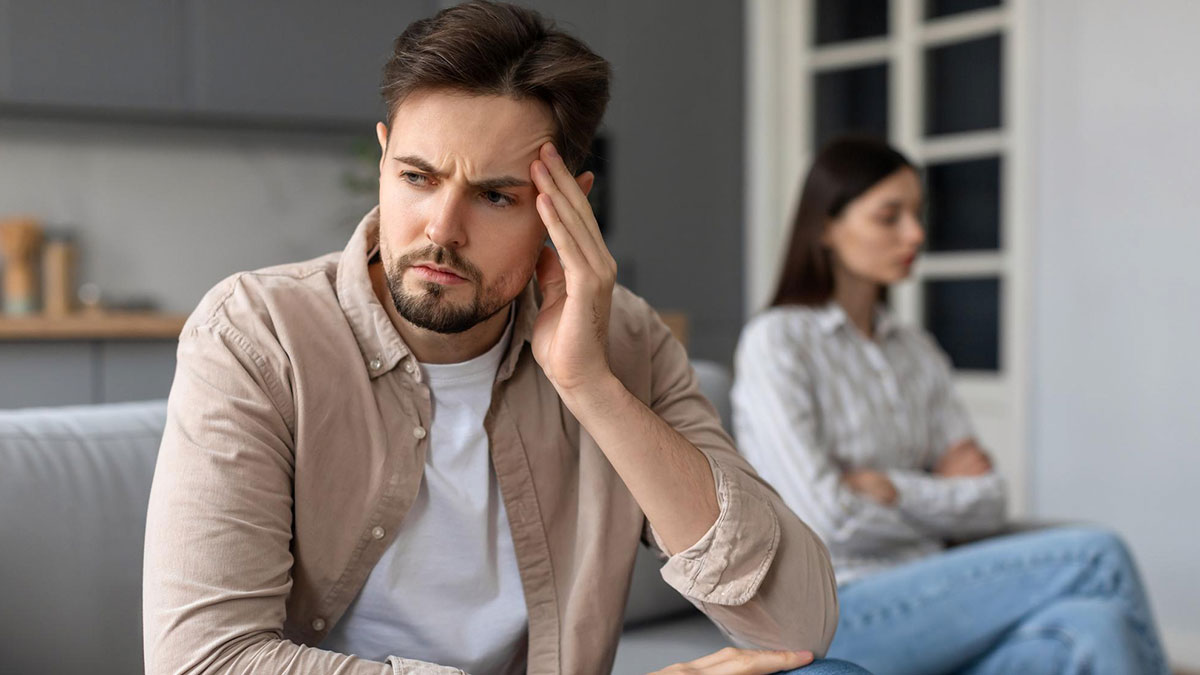 Man looking frustrated while fiancu00e9e sits upset in background, reflecting on stepparenting and parenting duties.