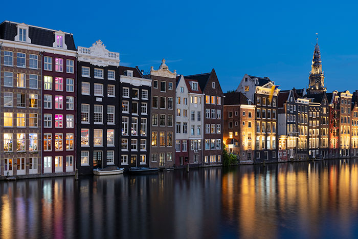 Evening view of historic canal houses reflecting in water, highlighting solo female travelers' safety concerns in popular destinations.