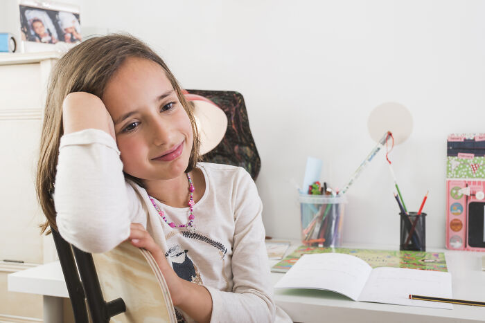 Young girl sitting thoughtfully at desk with open book, illustrating a creepy medical case doctors and nurses can never forget.