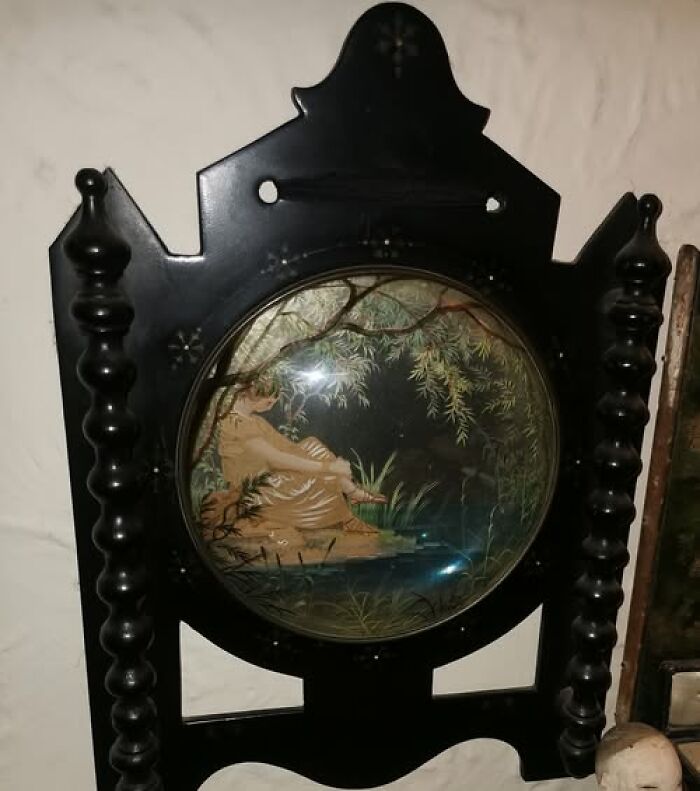 Victorian-Edwardian picture in a decorative black wooden frame with turned spindle sides showing a seated figure by a pond.