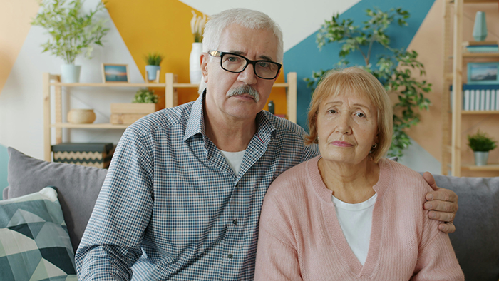 Elderly couple sitting on sofa looking concerned, illustrating toxic family dynamics and challenges faced at home. Elderly couple sitting on sofa looking concerned, illustrating toxic family dynamics and challenges faced at home.