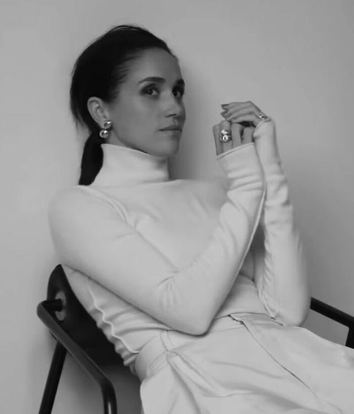Meghan Markle in a makeup-free cover photo, captured in black and white, sitting with hands clasped and hair tied back. Meghan Markle in a makeup-free cover photo, captured in black and white, sitting with hands clasped and hair tied back.