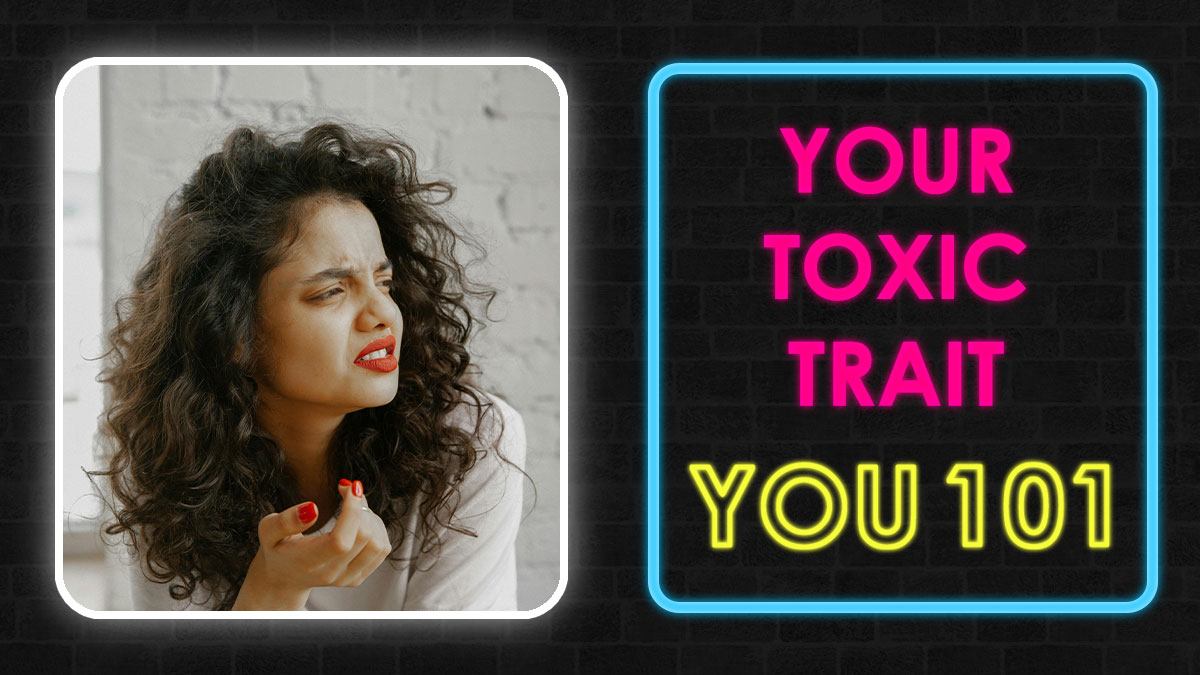 Woman with curly hair making a confused face next to neon sign reading your toxic trait you 101 against dark wall background