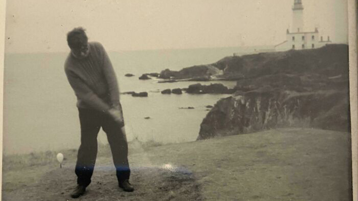 Man playing golf on a cliffside with rocky coastline and lighthouse in the background in a vintage photo for where was this taken.