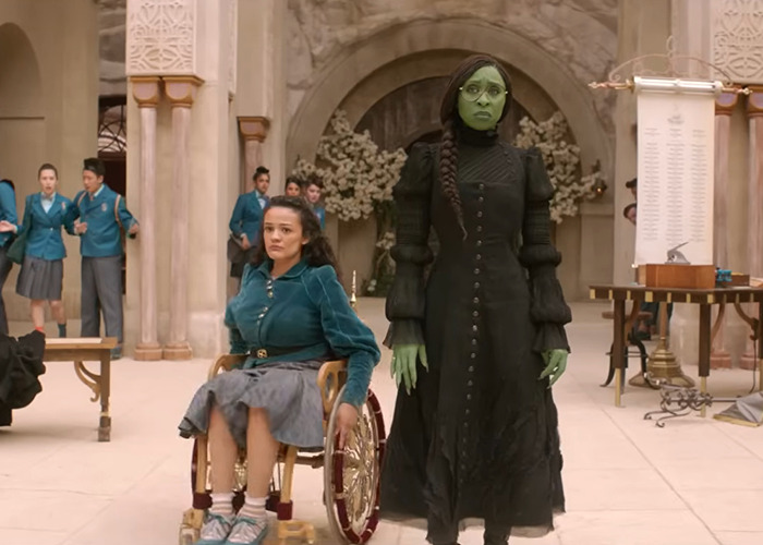 Wicked cast members in costume during a scene, highlighting a discussion on disability inclusion controversy. Wicked cast members in costume during a scene, highlighting a discussion on disability inclusion controversy.