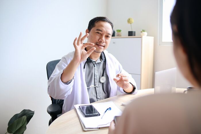 Doctor in white coat explaining cancer diagnosis to patient during a medical consultation in a bright office setting