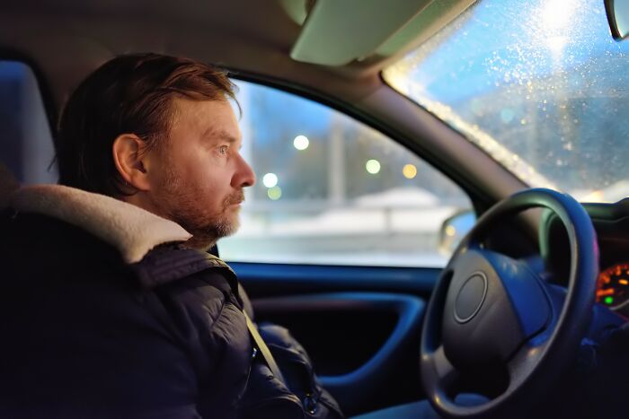 Man sitting in car looking thoughtful and upset, illustrating the emotional impact of insensitive things said to people having a hard time with cancer.