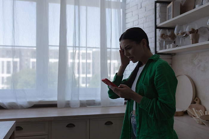 Woman in green shirt looking suspicious at phone, rethinking relationship after man’s suspicious work trip and possible block. Woman in green shirt looking suspicious at phone, rethinking relationship after man’s suspicious work trip and possible block.