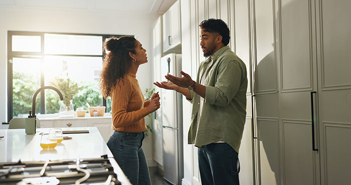 Couple having a tense conversation in the kitchen about a guy secretly giving his sister a key to girlfriend’s house.