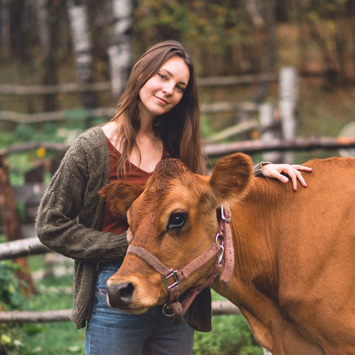 Woman standing in the woods with a cow, related to viral $15K cabin sparking safety concerns debate.