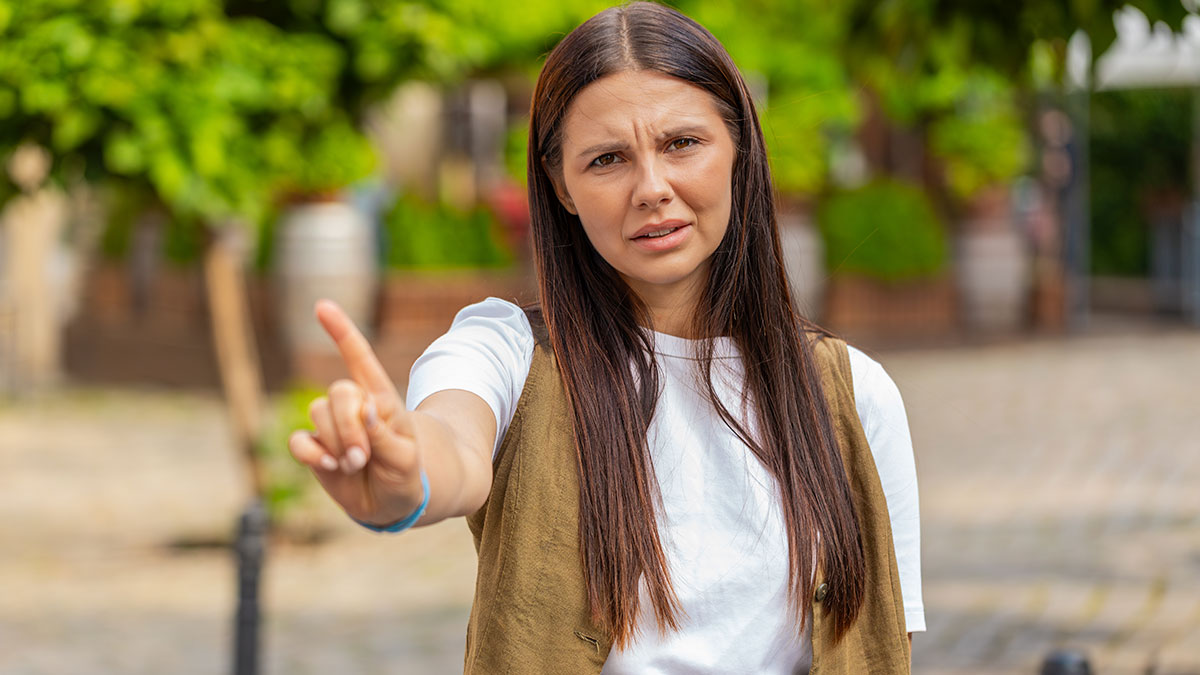 Woman pointing forward with serious expression outdoors, illustrating concerns about endangering a tween after drop-off.
