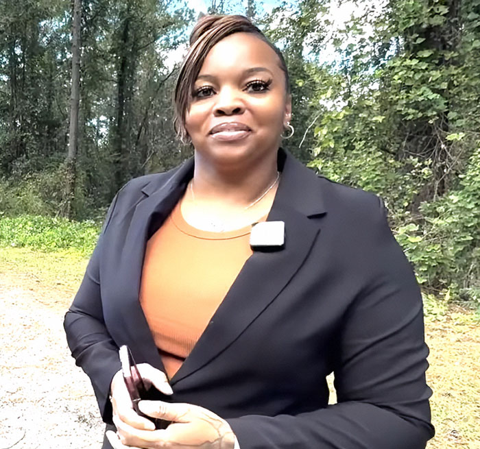 Woman outdoors in a black blazer discussing heated debate online about slaying escaped research monkey to protect children