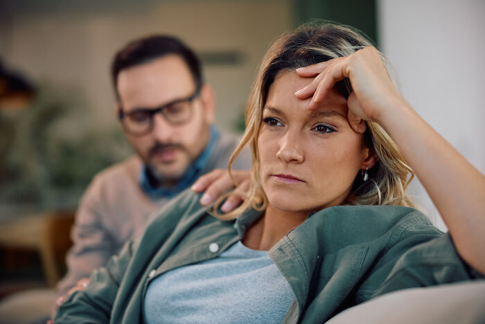 Woman preparing feast and feeling moody while husband looks on, symbolizing family tension during meal preparation. Woman preparing feast and feeling moody while husband looks on, symbolizing family tension during meal preparation.