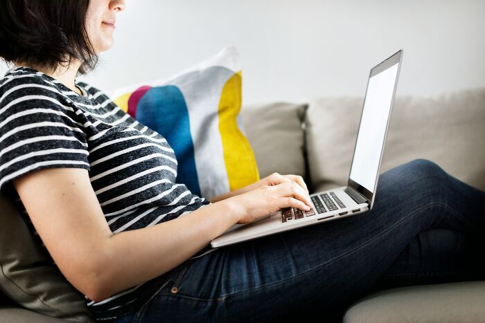 Woman sitting on couch using laptop, concerned about lonely widower fixating and appearing everywhere she goes. Woman sitting on couch using laptop, concerned about lonely widower fixating and appearing everywhere she goes.
