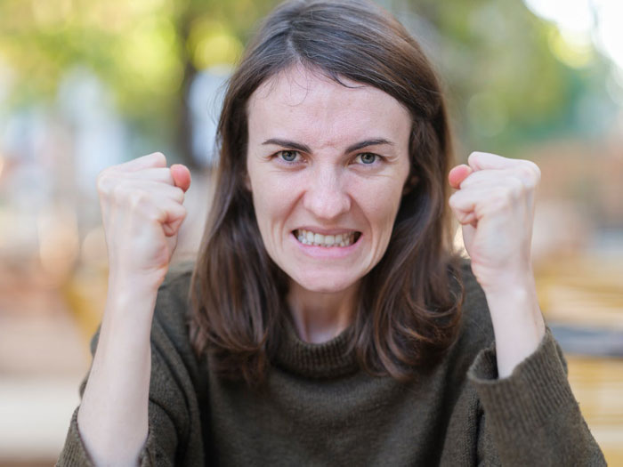 Angry woman with clenched fists expressing frustration after being denied entrance at a private party.