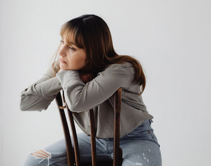 Entitled mother looking upset and frustrated after being denied entrance at a private party, sitting on a chair.