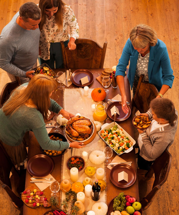 Family gathering around a traditional Thanksgiving meal with roasted turkey and autumn decorations on wooden table. Family gathering around a traditional Thanksgiving meal with roasted turkey and autumn decorations on wooden table.