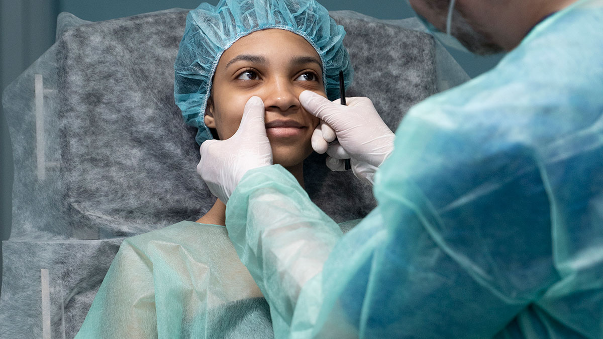 Woman during plastic surgery consultation with doctor, discussing procedure related to body dysmorphia concerns.
