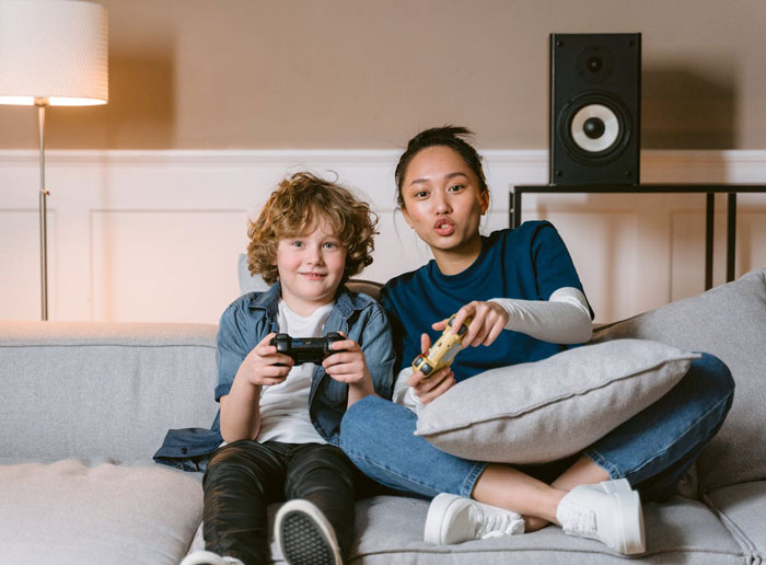 Woman and nephew playing video games together on a couch, capturing the moment woman took back nephews Christmas gift.