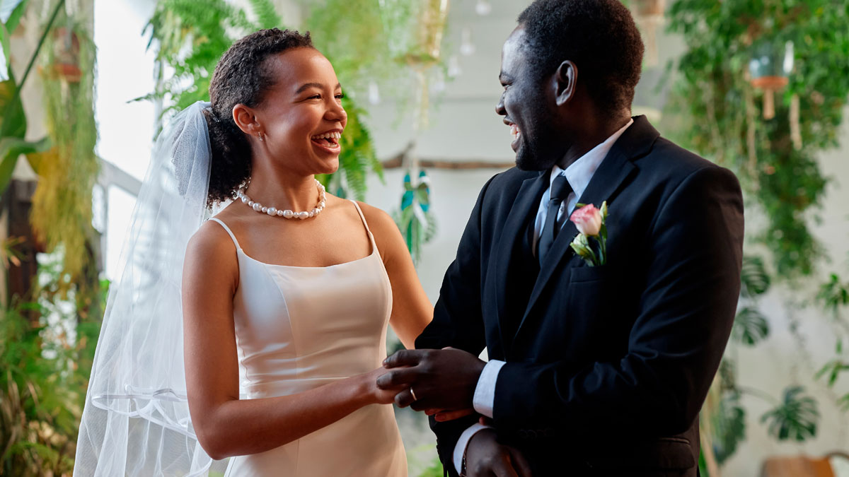 Smiling woman giving brother a papaya as birthday gift, playfully calling him cheap in a bright indoor setting