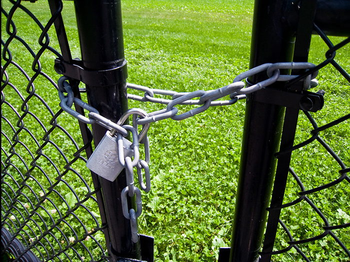 Locked black metal gate with chain and padlock securing a pool area symbolizing neighbor disputes over pool access rules Locked black metal gate with chain and padlock securing a pool area symbolizing neighbor disputes over pool access rules