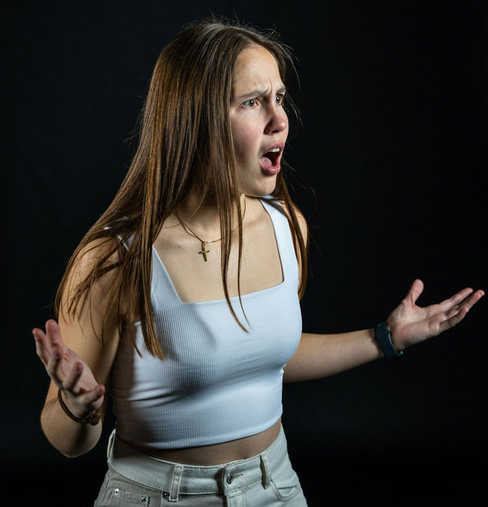 Young woman in a white top expressing frustration, illustrating a story about stealing and losing money from a sister-in-law’s book.