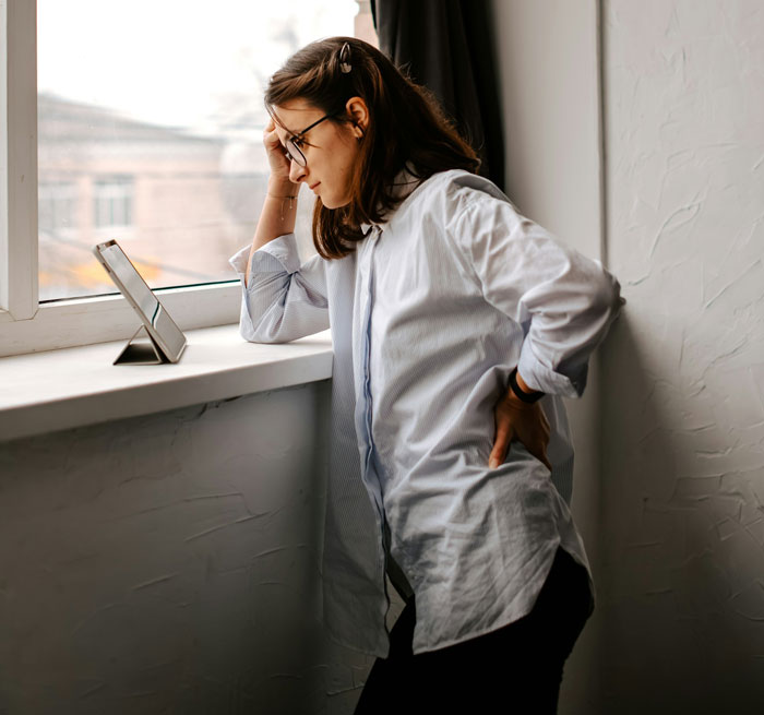 Woman leaning on windowsill looking at tablet, reflecting on book theft and publishing loss involving sister-in-law's work