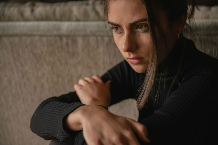 Woman sitting thoughtfully, appearing upset and reflective, illustrating storytelling about book theft and loss.