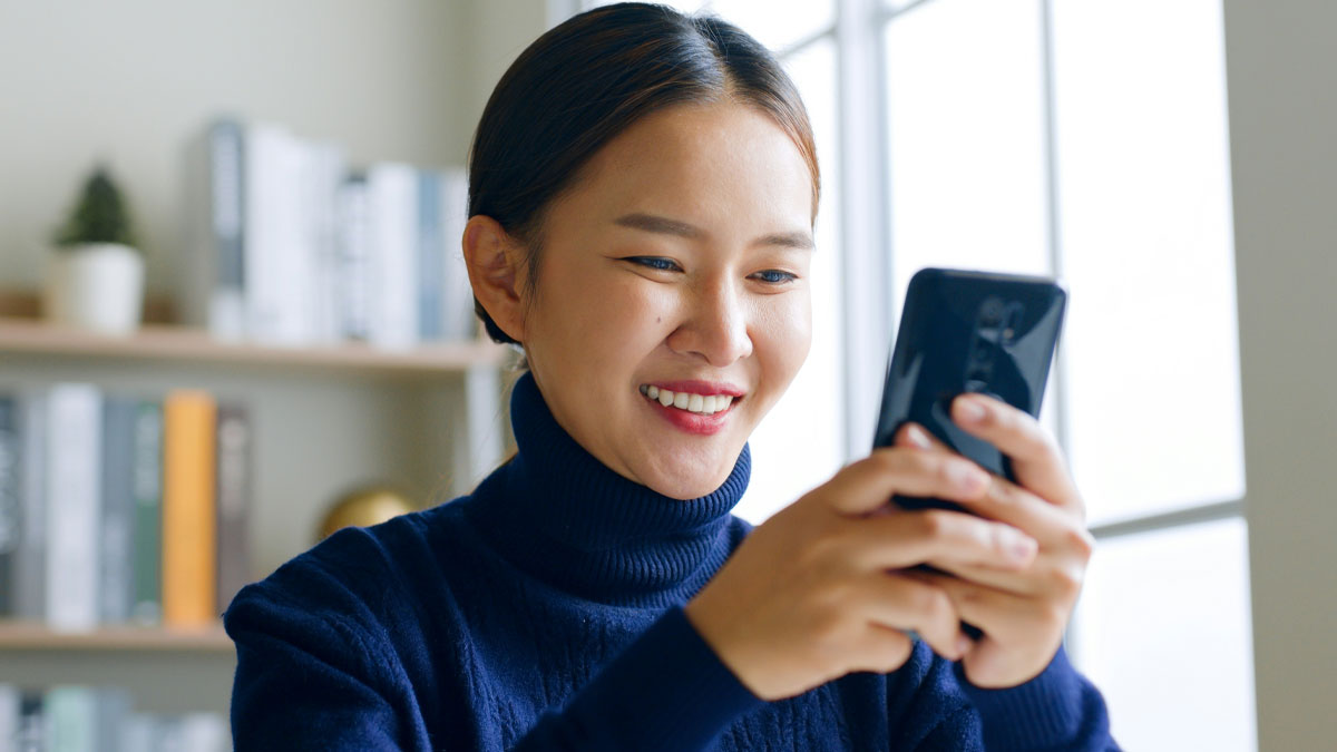 Young woman smiling and engaging with her phone, representing savage women who roasted men online confidently.