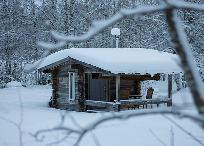 Small wooden cabin covered in snow during winter, illustrating worst night’s sleep due to the place they were in.