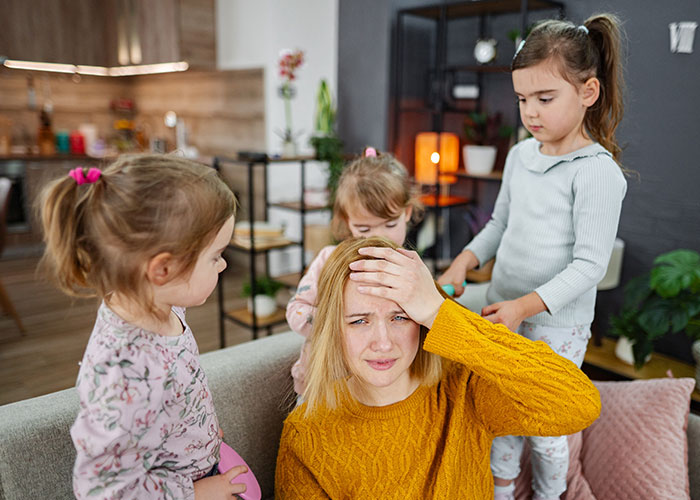 Teen looking frustrated while babysitting step-siblings at home, illustrating tension in family dynamics and childcare duties.