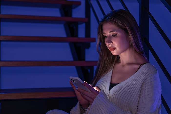 Young woman sitting on stairs at night, focused on her phone, reflecting on borrowing a car for one hour then keeping it days.